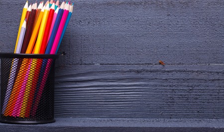 Palette set of colorful sharp pencils brown red yellow blue violet pink purple lilac grey black white and orange colors standing in cup on wooden background copyspace, horizontal pictureの写真素材