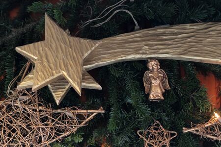 Close-up picture of shiny silver star and little angel tree toy hanging on Christmas tree and creating festive moodの写真素材