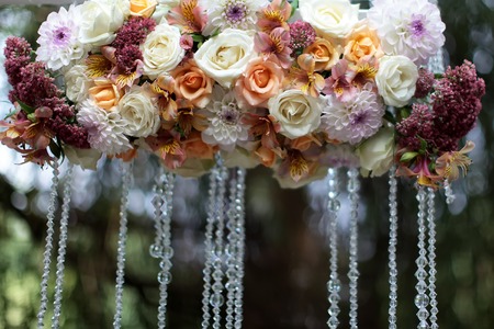 Closeup of beautiful fresh colorful wedding decorative arrangment of rose alstromeria and chrysanthemum with crystal beads outdoor on blurred natural background in sunlight, horizontal pictureの写真素材