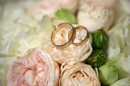 Closeup view of beautiful fresh soft wedding decorative bouquet of pink rose white peony and green flowers with two golden rings, horizontal picture