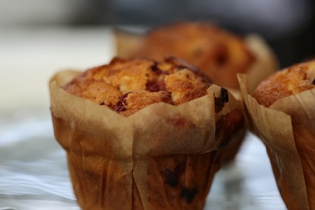 Closeup of some homemade sweet delicious chip berry muffins in muffin case on white background, horizontal pictureの写真素材