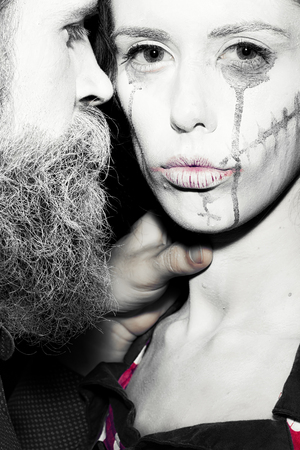 Closeup view of couple of painted halloween holy chrackters woman and man with long lush beard looking forward on studio wall background black and white, vertical pictureの写真素材
