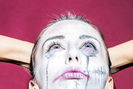 Portrait closeup view of one halloween holiday celebration charackter young woman with spooky painted face of zombi looking away on purple studio wall background, horizontal pictureの写真素材