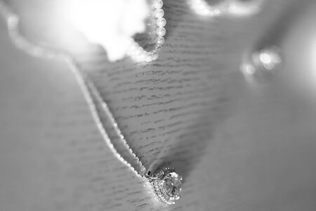 Closeup elegant jewellery pendant ornament in shape of heart with crystals and pearl rope on blurred black and white background, horizontal pictureの写真素材