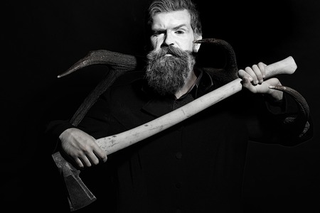 Portrait closeup view of one senior man with spooky painted face of zombi and long white lush beard holding animal antlers and axe black and white, horizontal pictureの写真素材