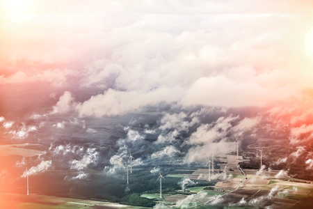 Panorama spectacular skyline view with light-exposed spot of cloudy blue sky from airplane window over windfarm landscape background wind turbines renewable power energy stations, horizontal pictureの写真素材