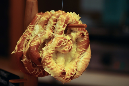 Closeup some delicious fresh baked cracknels in glaze hanging on wooden stand over blur bacground, horizontal pictureの写真素材
