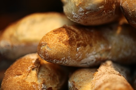 Closeup many fresh baked long thin loaves of whole French bread wheat baguette with crunchy crusts...