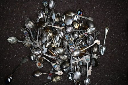 Closeup pile of empty shiny silver tea spoons with different diverse emblems on handles on cloudy stone background, horizontal pictureの写真素材