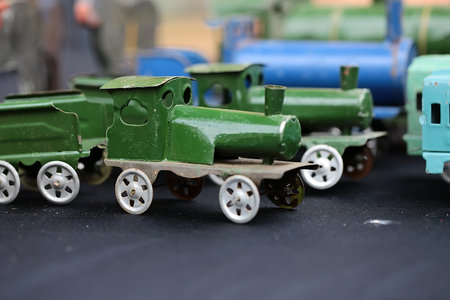 Closeup old retro metal scale model of steam train with whistle flute and wagon standing sideward on black cloth over blur toy collection background, horisontal pictureの写真素材