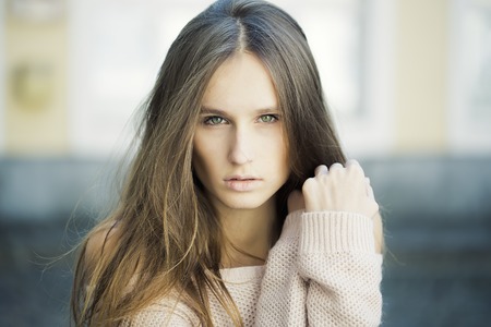 Closeup view of one beautiful sensual young stylish woman with blonde lush long hair and bare shoulders standing outdoor near street arch on blurred background, horizontal pictureの写真素材