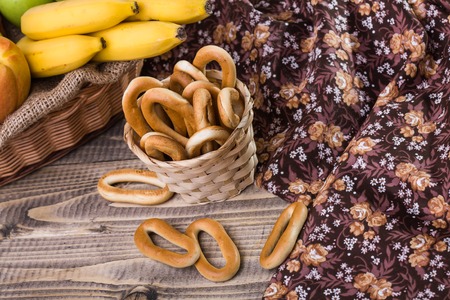 Photo top view of hard oval cracknels in basket with some bagels lying on wooden table next to...