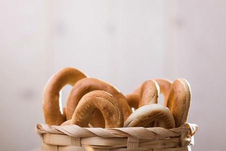 Photo still life closeup top of basket full of delicious hard oval cracknels peeking out heaped high over blurred rustic background, horizontal pictureの写真素材