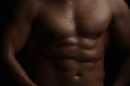 Closeup view of one handsome sexual strong young male bare chest of muscular body standing posing on studio background, horizontal pictureの写真素材