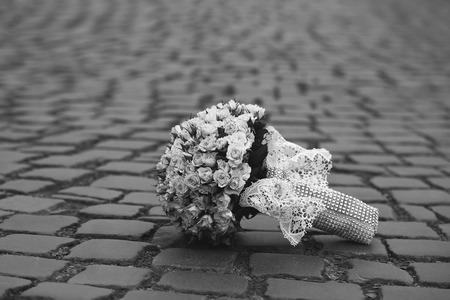 Closeup view of one beautiful fresh bright white yellow big wedding bouquet of rose flowers lying on grey road outdoor on natural background, horizonbtal pictureの写真素材