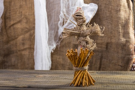 Photo still life of one sheaf of delicious stick biscuits straws tied together with string voodoo doll with sticks on chest standing on wooden table on blurred rustic background, horizontal pictureの写真素材