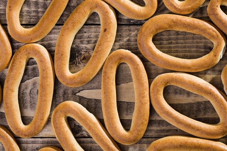 Photo top view closeup seamless mass of delicious hard oval cracknels poured out and laying on wooden table on timber background, horizontal pictureの写真素材