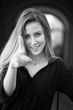Closeup portrait of one beautiful happy smiling blonde young woman with long hair outdoor looking forward on blurred background black and white, vertical pictureの写真素材