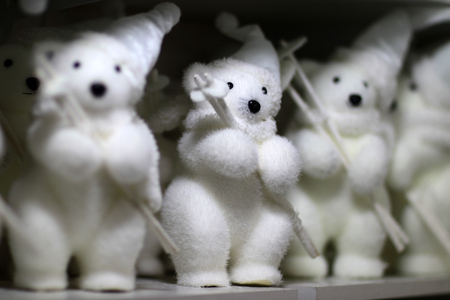 Closeup view of many little cute fluffy white tiy figures of white bears in hat and scarfs holding ski poles, horizontal pictureの写真素材