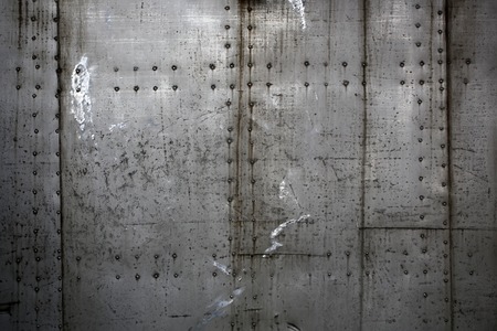 Photo closeup old rusty grunge steel aluminum fragment of protective structure made of metal plates sheets assembled with button head rivets on armor textured background, horizontal pictureの写真素材