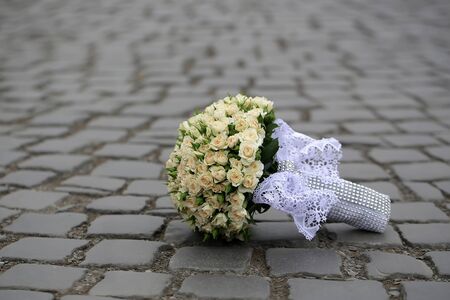 Closeup view of one beautiful fresh bright white yellow big wedding bouquet of rose flowers lying on grey road outdoor on natural background, horizonbtal pictureの写真素材