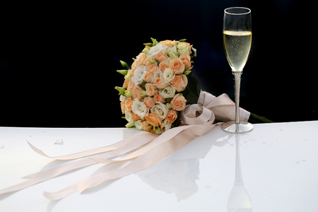 Photo side-on ball-shaped elegant wedding bouquet of fresh pastel pink white roses flowers with ribbons for bridal ceremony champagne glass on car hood over dark screen background, horizontal pictureの写真素材