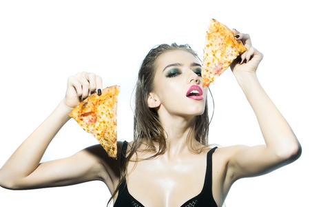 One pretty young sexy woman in black underwear with long wet hair and bright makeup holding tasty big slice of pizza ready to eat standing in studio on white background, horizontal pictureの写真素材
