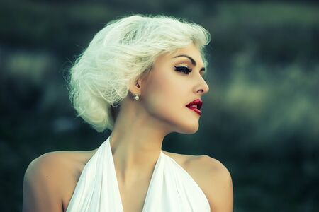 Closeup portrait of one attractive sensual dreaming young retro woman with blonde hair red lips in white dress in monroe style outdoor on natural background, horizontal pictureの写真素材