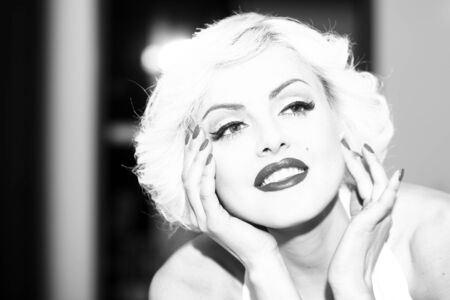 Closeup portrait of one attractive sensual dreaming young retro woman with blonde hair bright lips in dress in monroe style indoor on light background black and white, horizontal pictureの写真素材
