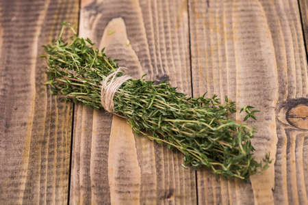 Bunch of aromatic spicy ripe rosemary herb tied by brown rope on wooden background closeup studio, horizontal pictureの写真素材