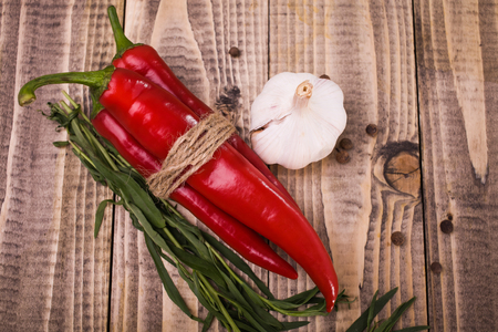 Bright red chili hot peppers tied by rope white clean garlic branches of eating herb spicy allspice vegetable harvest in autumn healthy lifestyle on wooden background studio top view, horizontalの写真素材