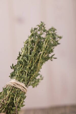 Bunch of aromatic herb condiment rosemary herbal natural ingredient with piquant flavour domestic eco product tied by rope on light blur background closeup indoor, vertical pictureの写真素材