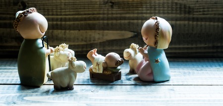 Closeup view of decorative celbrating Christmas and Jesus birth figurines of holy vergin Mary Josepd newborn child with few white sheeps standing on wooden background, horizontal pictureの写真素材