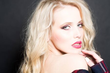 Closeup view of one attractive sexual passionate blonde woman with long curly hair standing in...
