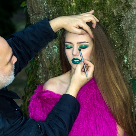 One pretty fashionable young woman with long hair and emeral bright makeup in purple fur waist coat...