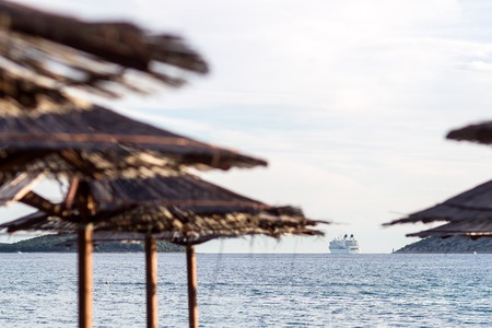 Photo of beautiful white modern ocean passenger liner in blue sea seaside mountains beach umbrellas...