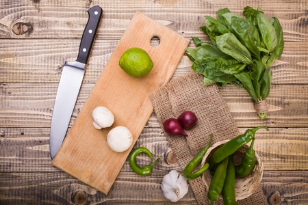 Top view of two whole raw champignons fresh lime on cutting board bunch of basil garlic purple...