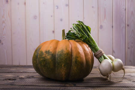 Autumn rural still life of big raw orange pumpkin with green spots and bunch of fresh pure white...