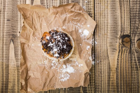 Delicious fresh baked cupcake snack decorated by chocolate pieces and powdered sugar standing on...