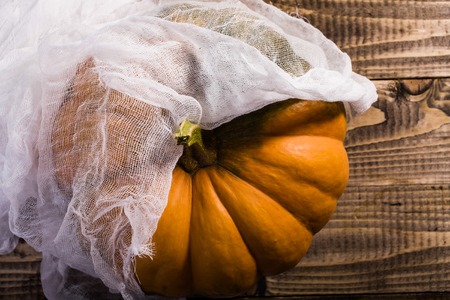 Top view of big bright whole ripe round orange segmented squash with peduncle covered with white cheesecloth, horizontal photoの写真素材