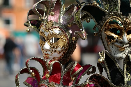 Photo closeup of distinctive Venetian carnival masks with beautiful decoration hand painting ornate classic accessory on display for sale outdoor on blurred background, horizontal pictureの写真素材