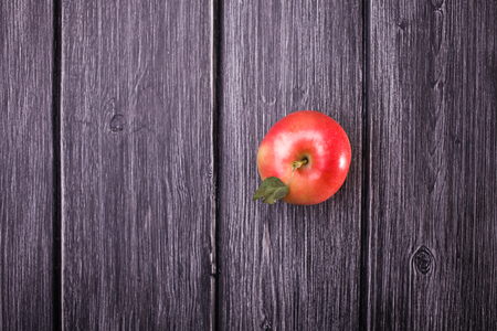 Top view of whole sweet raw red yellow apple with green leaf on shank on grey wooden timber background, horizontal photoの写真素材