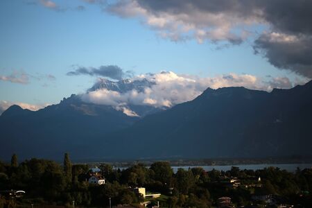 MONTREUX, SWITZERLAND - September 18, 2015: Panoramic view on Lake Geneva and alpine mountains covered with clouds from city Montreux in autumn, horizontal photoのeditorial素材