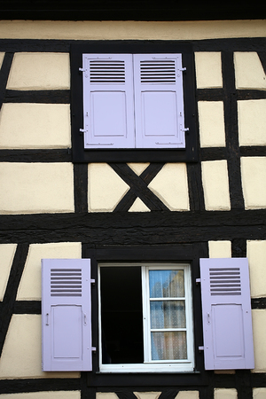 COLMAR, FRANCE - September 18, 2015: Windows with wooden shutters in half-timbered beige house in Colmar, vertical photoのeditorial素材
