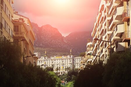 Beautiful urban natural landscape apls mountain with bright red sub beam between high fashion multistory buildings outdoor, horizontal pictureの写真素材