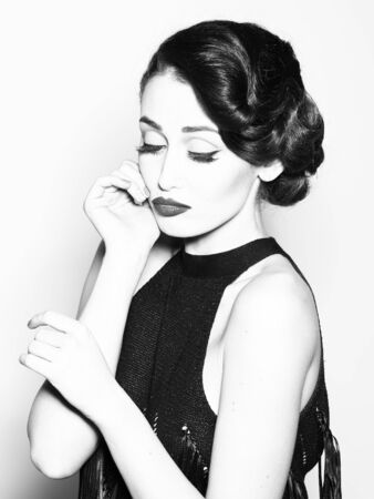 Portrait of attractive sensual glamour retro elegant young adult pensive woman with classic hairstyle and red lips in evening dress indoor black and white, vertical pictureの写真素材
