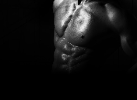 Gorgeous muscular naked sexy shining male torso with strong athletic chest and berfect pectoral and abdominal muscles on sporting belly black and white on dark background studio closeup, horizontalの写真素材