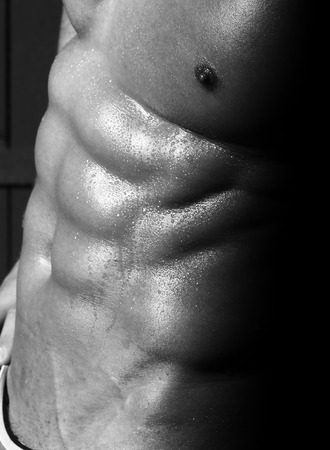Excellent sexual male naked muscular torso with perfect 6 pack abdominal pectoral muscles covered with drops sporting body of sweat black and white background studio closeup, vertical pictureの写真素材