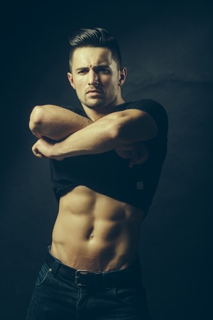 Handsome sensual sexy young stylish thoughtful man in black shirt with fashionable hairdo undressing