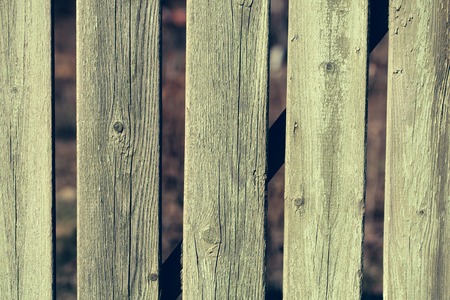 Distant boarded fence old wooden palisade wood boards with knots faded green paint closeup on timber backgroundの写真素材
